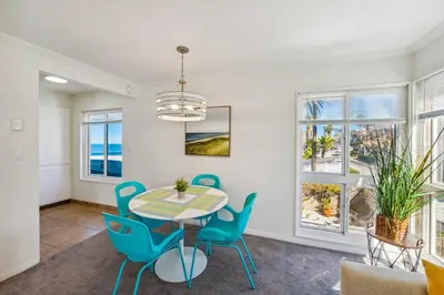 a dining room with a table and chairs and windows at Seas the Day by Cardo - La Jolla Beachfront in San Diego
