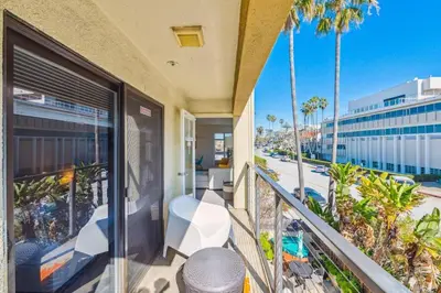 a balcony with a view of the beach and palm trees at Seas the Day by Cardo - La Jolla Beachfront in San Diego