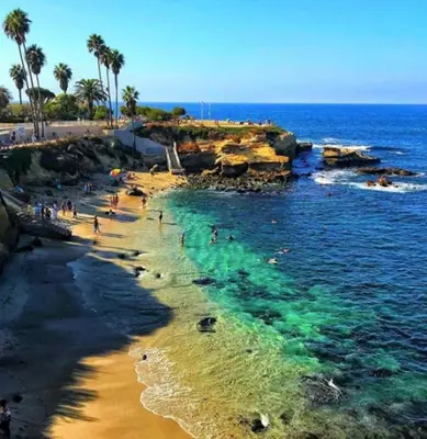 a group of people on a beach near the ocean at Seas the Day by Cardo - La Jolla Beachfront in San Diego