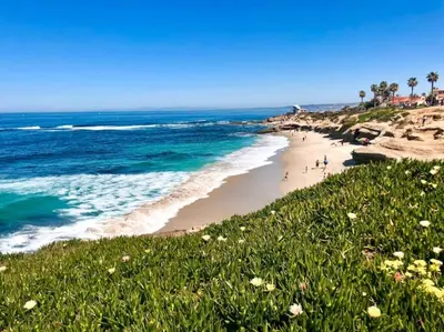 a beach with people walking on the sand and the ocean at Seas the Day by Cardo - La Jolla Beachfront in San Diego