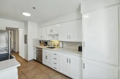 a large white kitchen with white cabinets and appliances at Seas the Day by Cardo - La Jolla Beachfront in San Diego