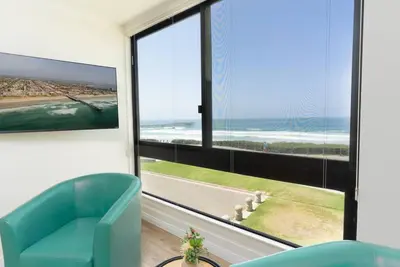a living room with a blue chair and a large window at Sunny on the Ocean - Beachfront- Pacific Beach in San Diego