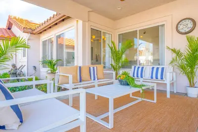 a porch with white chairs and a table and a clock at Luxury poolside « Villa Descanso » with heated pool and Spa! Close to San Diego/ Legoland in Oceanside