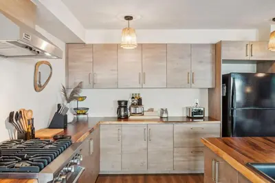 a kitchen with wooden cabinets and a black refrigerator at Living Lux in La Jolla - Beach - AC - Shops in San Diego