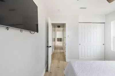 a white bedroom with a bed and a flat screen tv at Beach Home W AC- 5 BR - Free Parking - EV Charge in San Diego