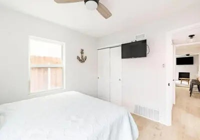 a white bedroom with a bed and a flat screen tv at Beach Home W AC- 5 BR - Free Parking - EV Charge in San Diego