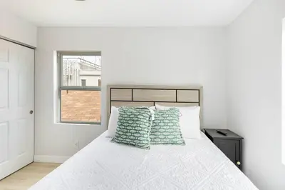 a bedroom with a white bed with green pillows at Beach Home W AC- 5 BR - Free Parking - EV Charge in San Diego
