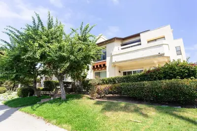 a large white building with a tree in the yard at Grand Desire - Vibrant - Luxury - Beachside treat in San Diego