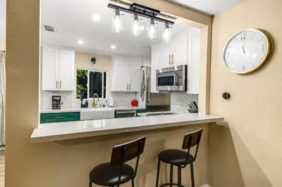 a kitchen with two bar stools and a clock on the wall at Buckthorn Beauty Private Hot Tub and Lounge Space in Pine Valley