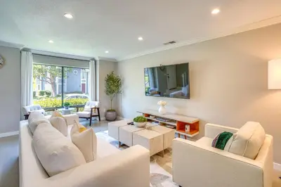 a living room with white furniture and a tv at Laguna Niguel Townhouse with Community Pool Access! in Laguna Niguel
