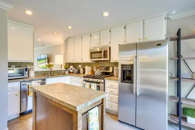 a kitchen with white cabinets and a stainless steel refrigerator at Laguna Niguel Townhouse with Community Pool Access! in Laguna Niguel