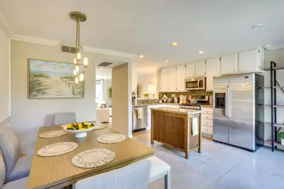 a kitchen with a wooden table and a dining room at Laguna Niguel Townhouse with Community Pool Access! in Laguna Niguel