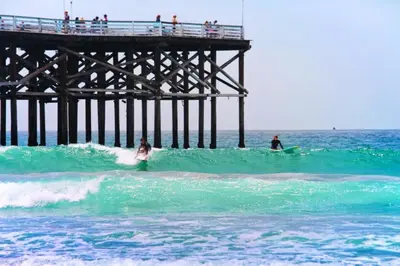 two people on surfboards in the ocean near a pier at Beach-2-Bay 1br - Mission Beach - AC - Shops in San Diego