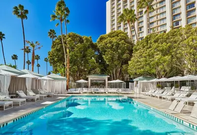 a swimming pool with lounge chairs and a building at Pendry Newport Beach in Newport Beach