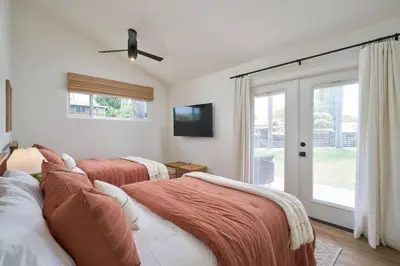 a bedroom with two beds and a tv and a window at Coastal Retreat with E-Bikes! in Carlsbad