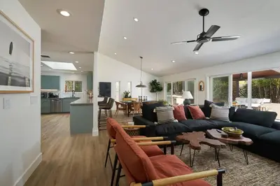 a living room with a black couch and a kitchen at Coastal Retreat with E-Bikes! in Carlsbad