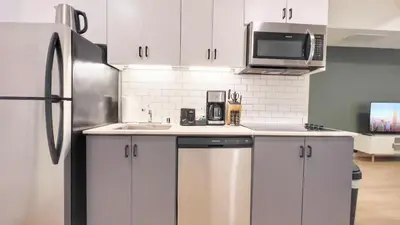 a kitchen with white cabinets and a stainless steel refrigerator at Dapper Retreat in Vibrant San Diego in San Diego