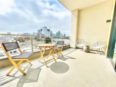 a balcony with chairs and a table and a view of a city at The Leo - Unit 602 in San Diego