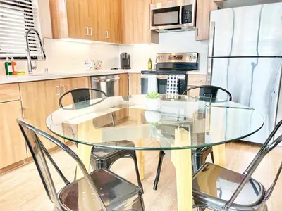 a glass table with four chairs in a kitchen at The Leo - Deluxe 3 Bedroom Stay in San Diego