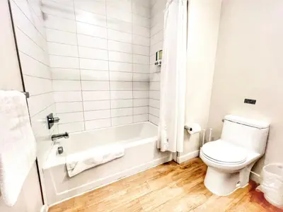 a white bathroom with a toilet and a bath tub at The Leo - Deluxe 3 Bedroom Stay in San Diego