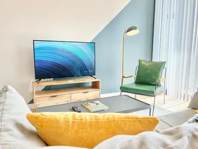 a living room with a tv and a green chair at Hidden Gem Apartment in Downtown in San Diego