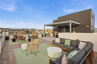 a rooftop patio with a couch and tables and chairs at San Diego Skyline - Downtown Apartment in San Diego