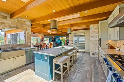 a kitchen with wooden ceilings and a blue island with bar stools at Casa Real | House in La Jolla in San Diego