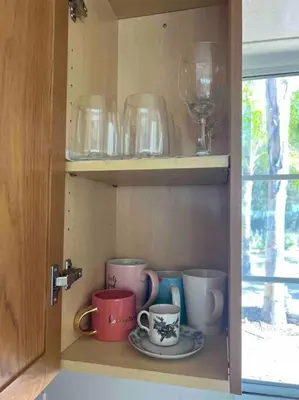 a cupboard with cups and glasses and a wine glass at The most breathtaking Lake and Mountain View in Fallbrook