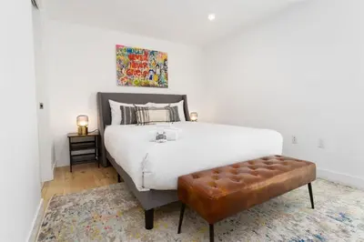 a bedroom with a large white bed with a brown stool at Bright and Trendy - Panoramic - Chic - Prime Location in San Diego