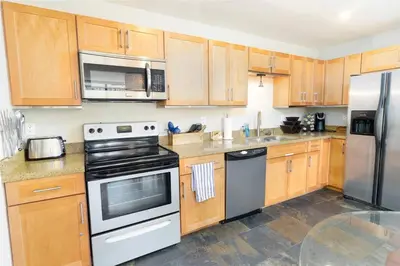 a kitchen with wooden cabinets and stainless steel appliances at Pineapple Paradise - Mission Beach - Stunning in San Diego