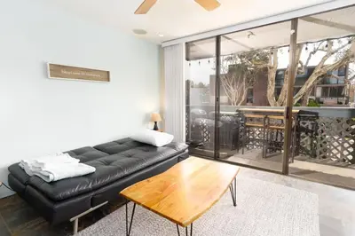 a living room with a black leather couch and a wooden table at Pineapple Paradise - Mission Beach - Stunning in San Diego