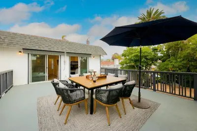 a wooden table with chairs and an umbrella on a patio at La Jolla Beach Retreat Compound in San Diego