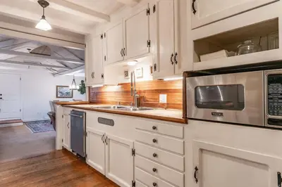 a kitchen with white cabinets and a sink and a microwave at Charming La Jolla Shores Cottage in San Diego