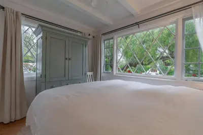 a bedroom with a large white bed and windows at Charming La Jolla Shores Cottage in San Diego