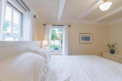a white bedroom with a large bed and a window at Charming La Jolla Shores Cottage in San Diego
