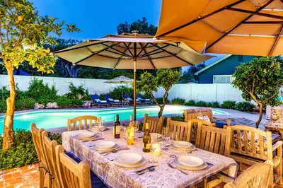 a table with chairs and umbrellas next to a pool at Charming La Jolla Shores Cottage in San Diego