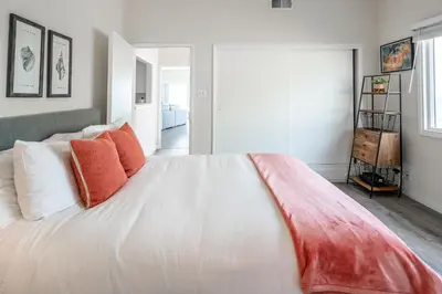 a bedroom with a large white bed with orange pillows at CB-2445D - Located on the Sand- Casa De Los Suenos in Carlsbad