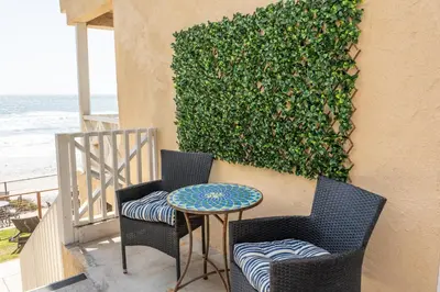 a patio with two chairs and a table and a hedge at CB-2445D - Located on the Sand- Casa De Los Suenos in Carlsbad