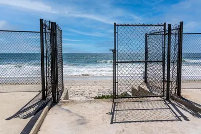 a gate on a beach with the ocean in the background at CB-2445D - Located on the Sand- Casa De Los Suenos in Carlsbad