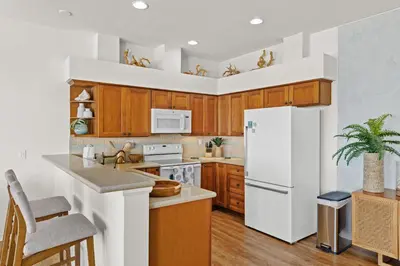 a kitchen with a white refrigerator and wooden cabinets at SB-767D - Soothing Solana Oceanfront Condo in Solana Beach