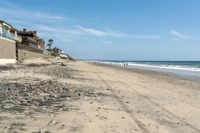 a sandy beach with people walking on the ocean at CB-2445C - Carlsbad Casa De Los Sueños | Unit C in Carlsbad