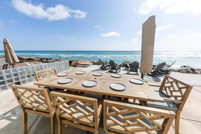 a wooden table and chairs on the beach at Stunning Oceanfront Home - Incredible Views in Oceanside