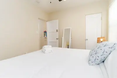 a bedroom with a white bed with a pillow and a mirror at Artfully-styled bungalow in the heart of it all in San Diego