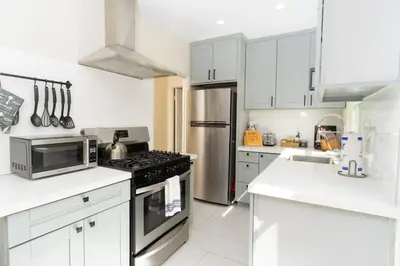 a kitchen with white cabinets and a stainless steel refrigerator at Artfully-styled bungalow in the heart of it all in San Diego