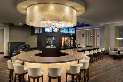 a bar with white chairs and a large chandelier at Courtyard by Marriott Irvine Spectrum in Irvine