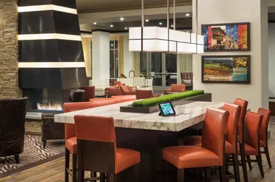 a restaurant with a large bar with orange chairs at Courtyard by Marriott Irvine Spectrum in Irvine