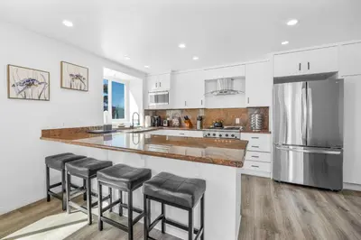 a kitchen with white cabinets and a stainless steel refrigerator at Ocean & Bay Panorama 4 Levels Rooftop with Hot Tub in San Diego
