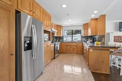 a kitchen with wooden cabinets and a stainless steel refrigerator at 3 Living Rooms - Spacious - Family-Friendly in National City