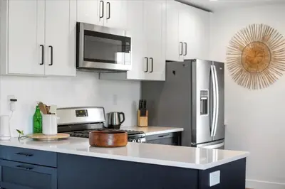 a kitchen with white cabinets and a stainless steel refrigerator at NEW Beautiful BOHO Home by Beach, Downtown + Shops in San Diego