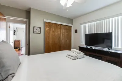 a bedroom with a large white bed and a flat screen tv at Family Retreat by Cardo - Sleeps 10 in National City